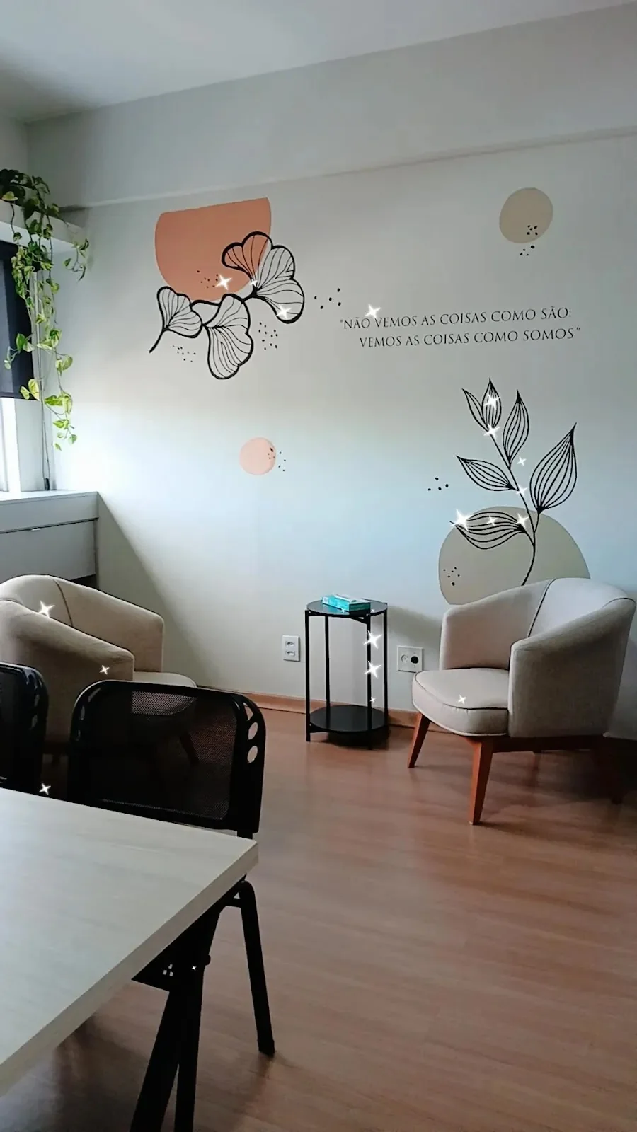 Sala de espera do consultório, com poltronas claras, planta e parede decorada com folhas